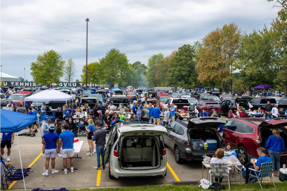 Overview picture of cars and people during Family Day tailgate.